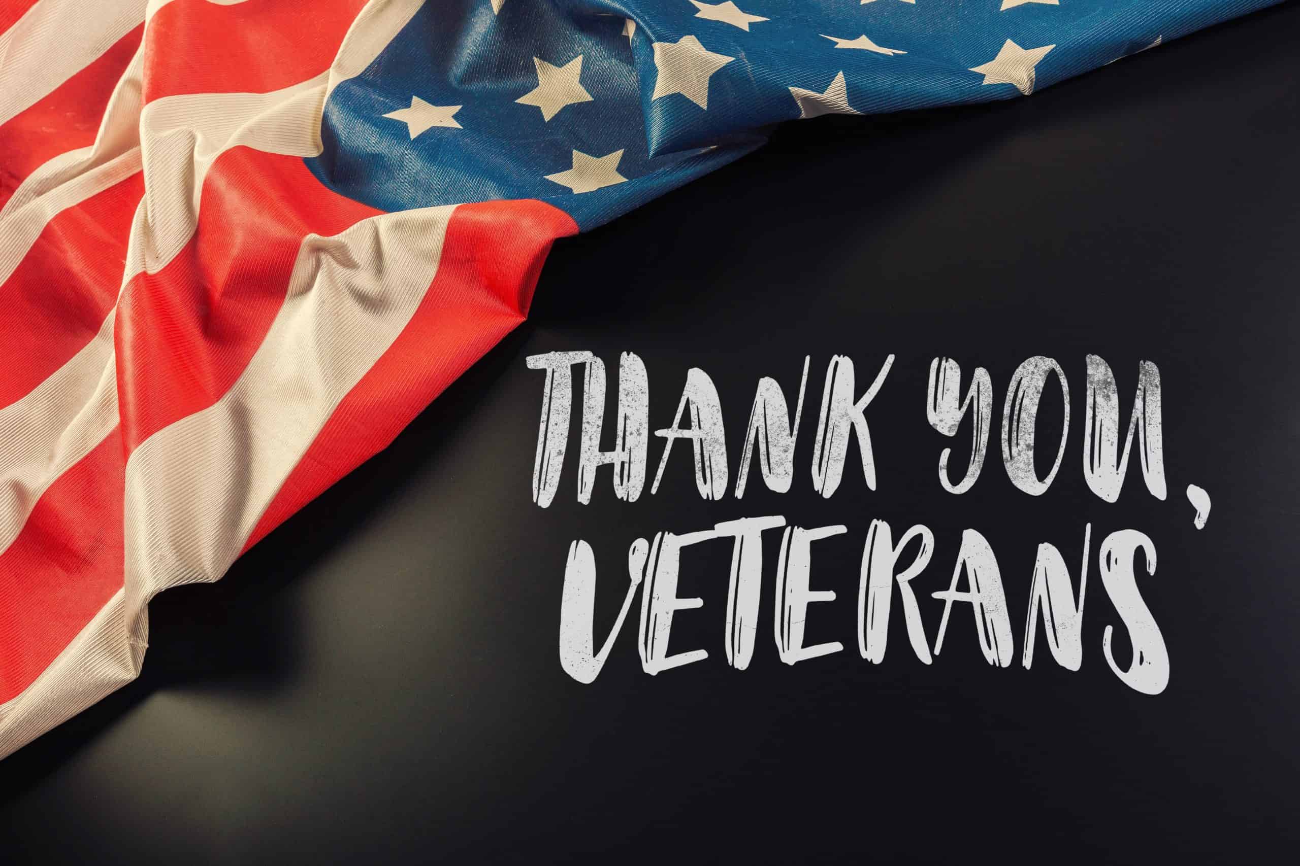 "Thank You, Veterans" lettering beside a folded American flag on a dark background.