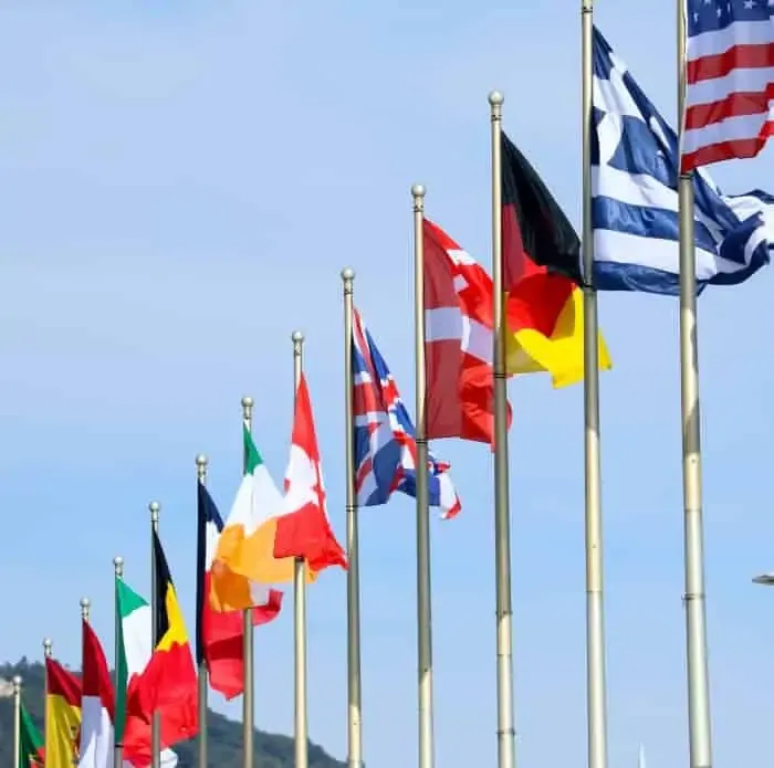 A receding row of national flags on tall poles against a clear blue sky.