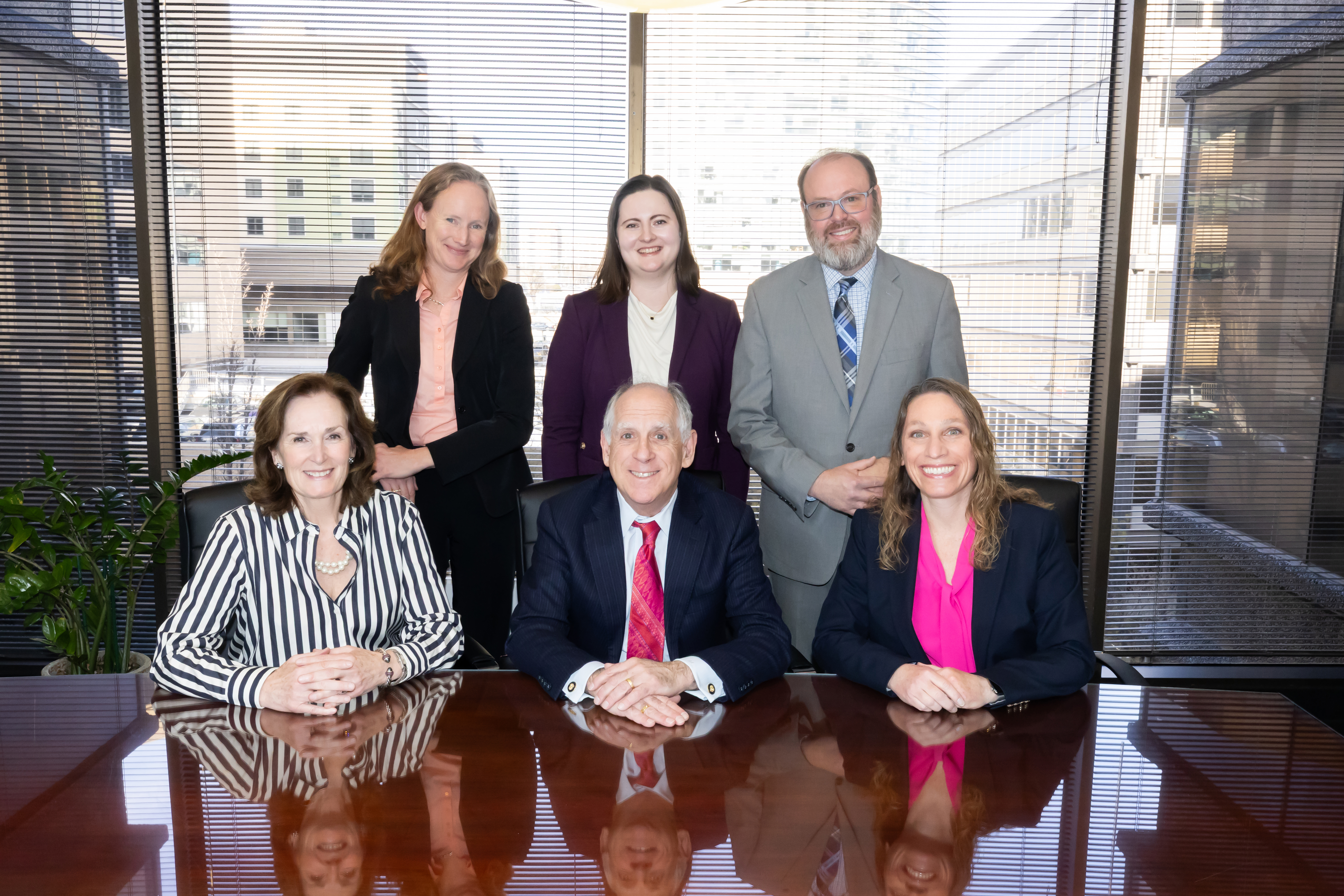 The Altman & Associates attorneys gathered around a conference table by a city-view window.