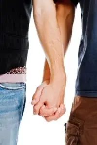 Two men hold hands, shown from the waist down against a white background.