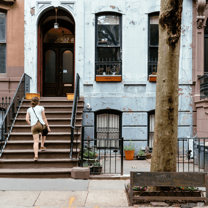 A woman walking up the steps to her townhouse.