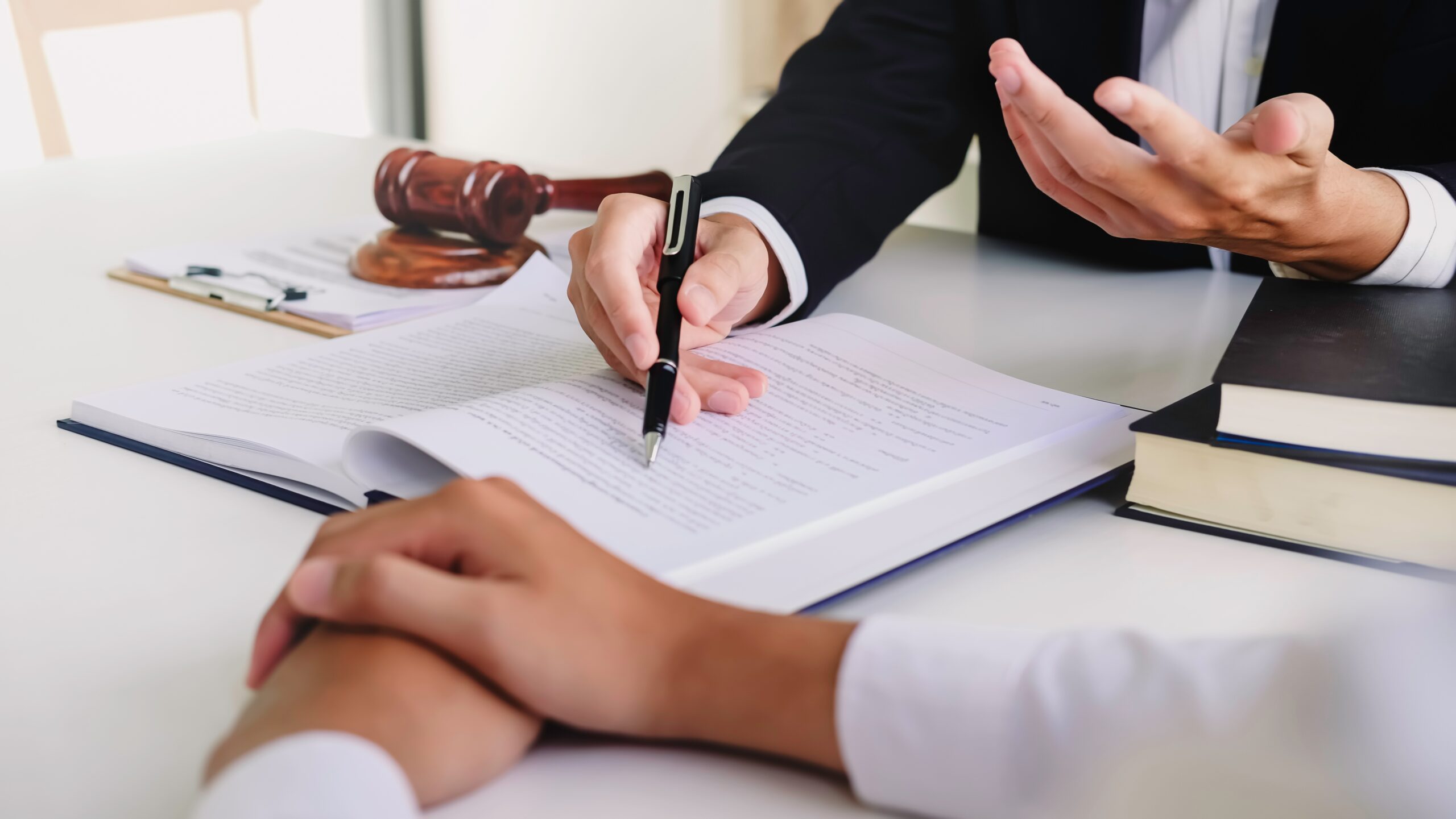Lawyer speaking with a client while writing in a notebook with a pen.